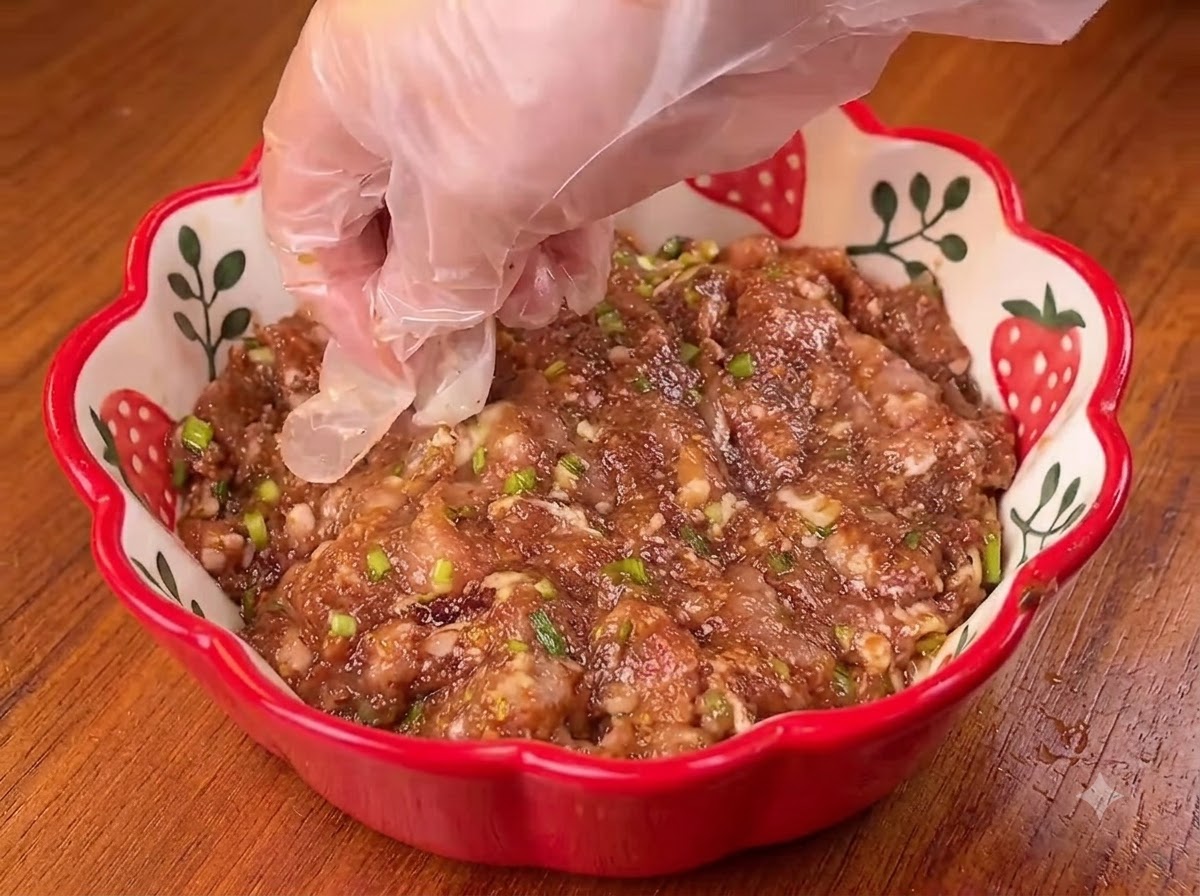 木製のボードの上で、木製のめん棒を使って丸いネギ餅の生地を平らに伸ばしている様子。