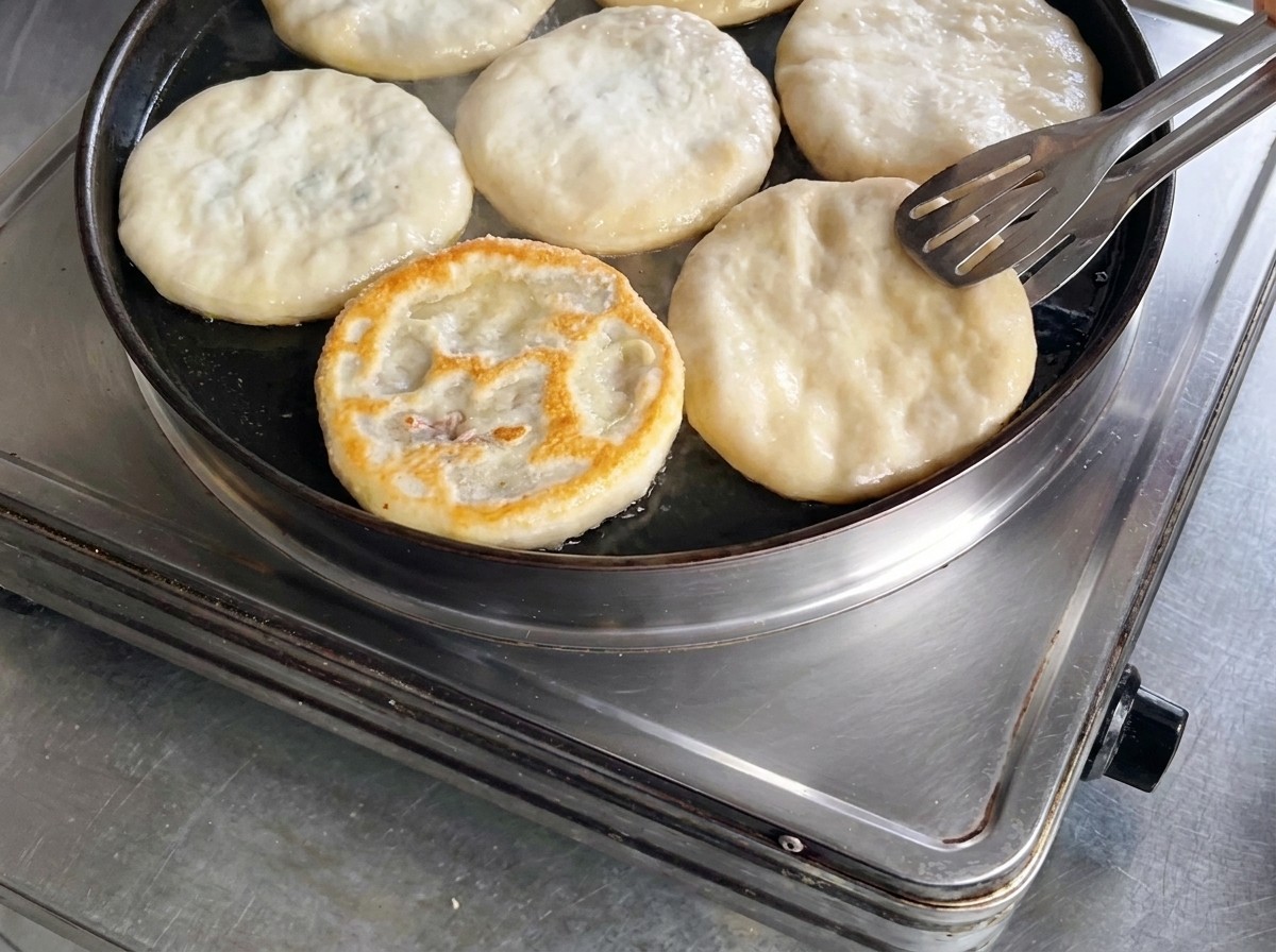 トングを使ってミートパイを裏返し、こんがりと綺麗に焼き色がついた表面を確認している様子。