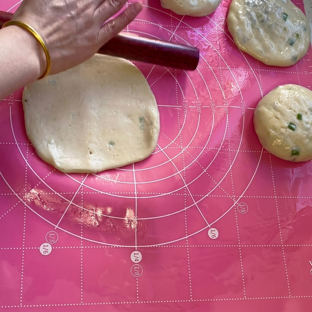 麺棒を使って生地を薄い円形に伸ばす様子