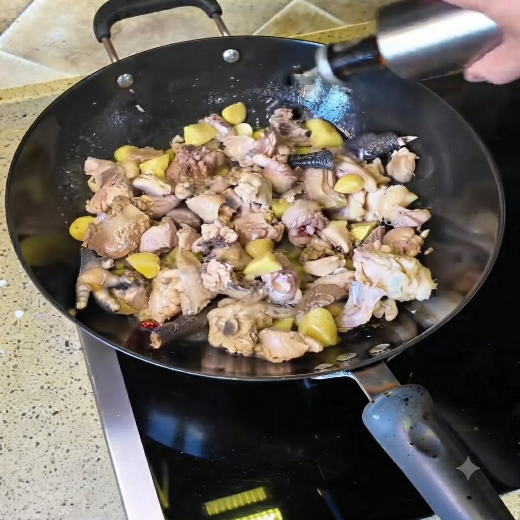 炒めている鶏肉の入った中華鍋にボトルから黄酒を注ぎ入れる様子