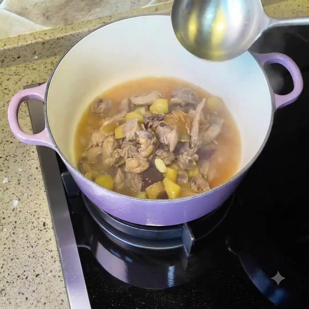 紫色のダッチオーブンで鶏肉とスープを煮込んでいる様子。そばにお玉が置かれている。