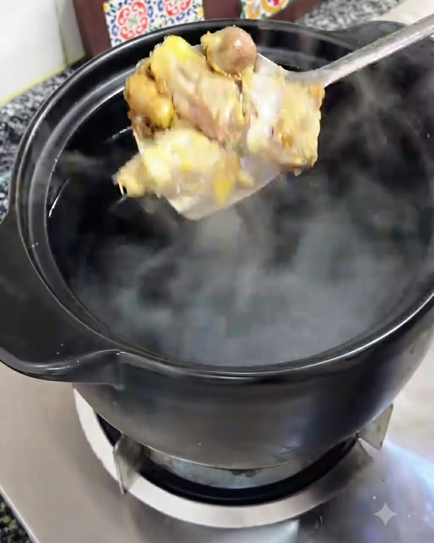 きつね色に炒められた鶏肉がスプーンで持ち上げられ、沸騰したお湯が入った黒い土鍋に移される様子。