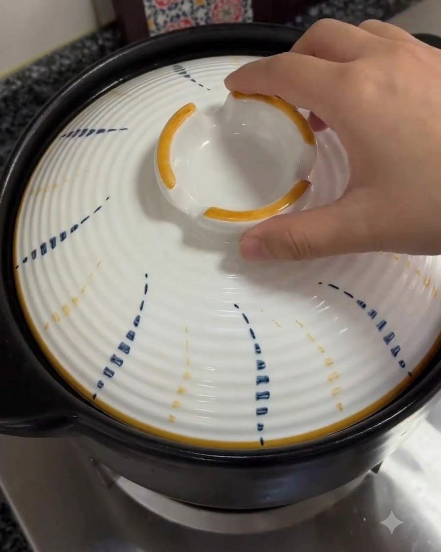 煮立っている土鍋に、模様のある白い蓋を再び置いている手。