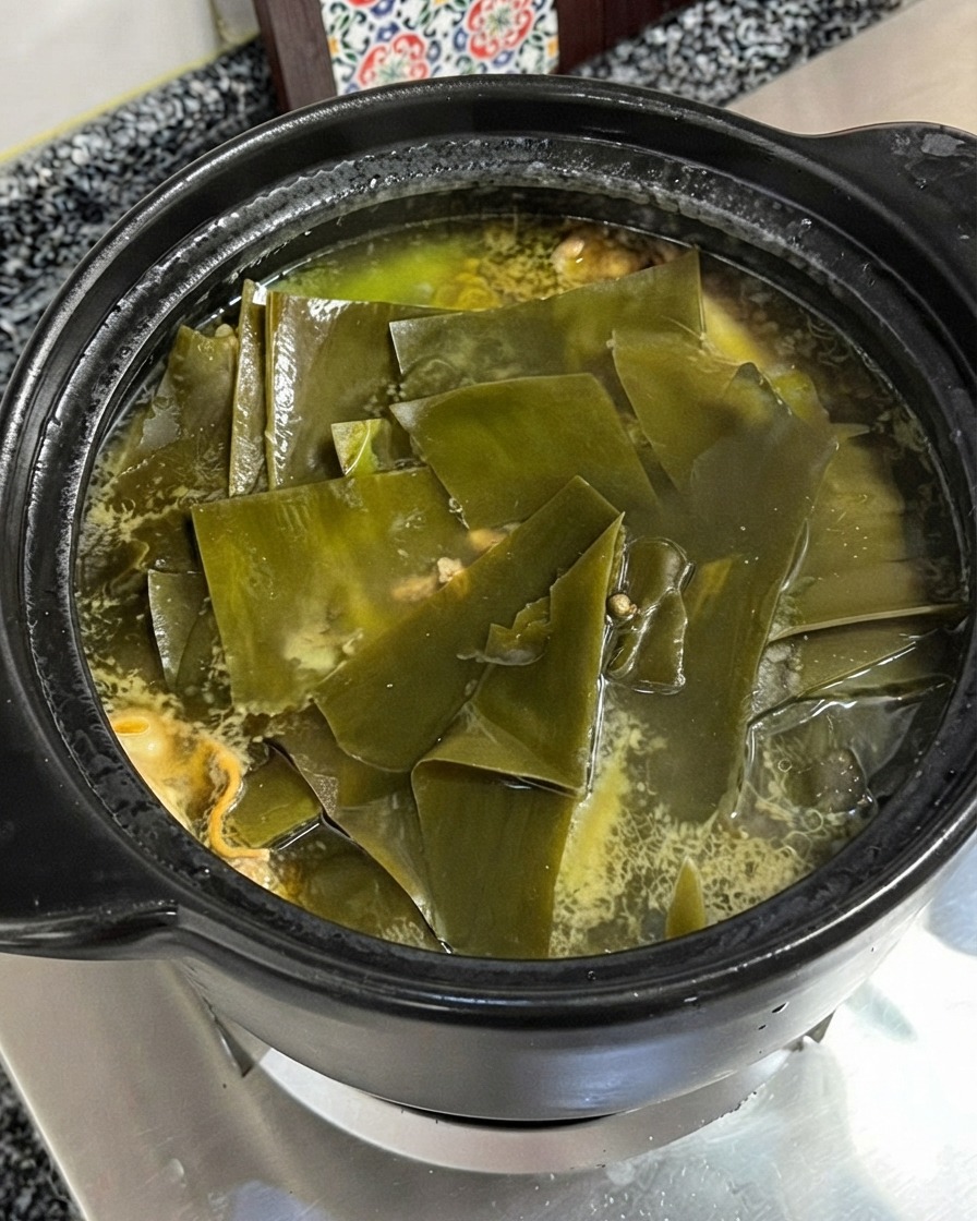 チキンと昆布のスープが煮立っているところに、鶏ガラスープの素が加えられている様子。