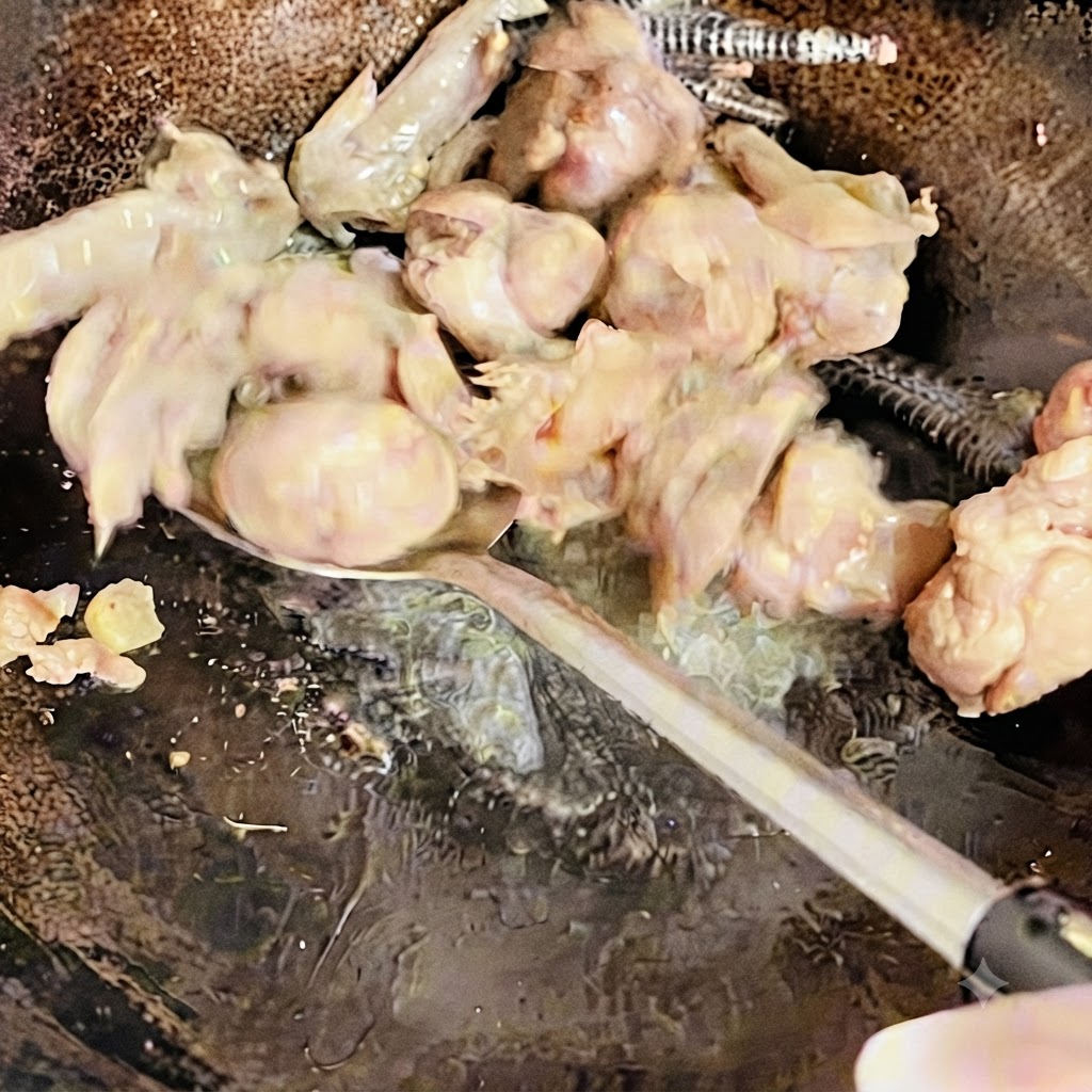 中華鍋で鶏肉をヘラでかき混ぜながら、軽く焼き色がつくまで炒めている様子