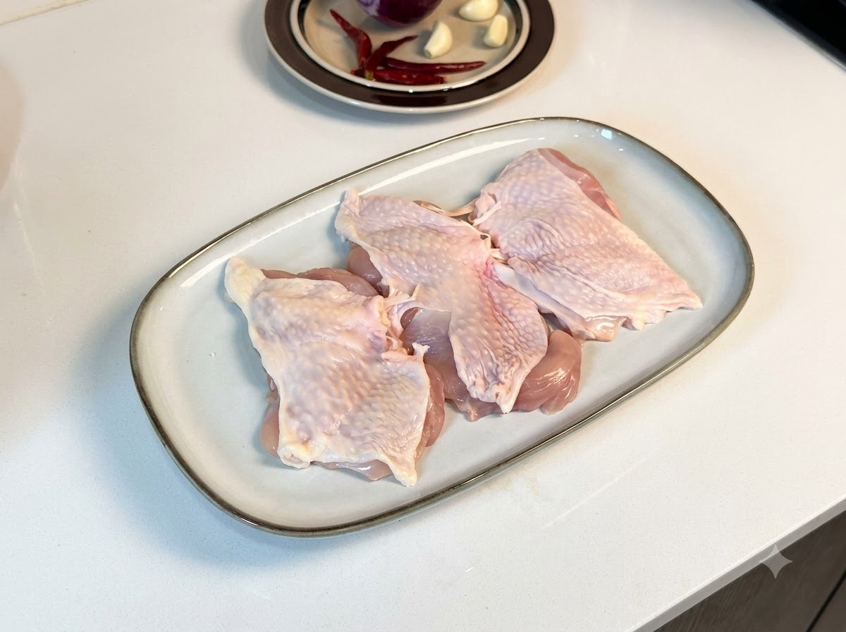 白い長方形の皿に並べられ、黒こしょうや調味料がまぶされた骨なし鶏もも肉。