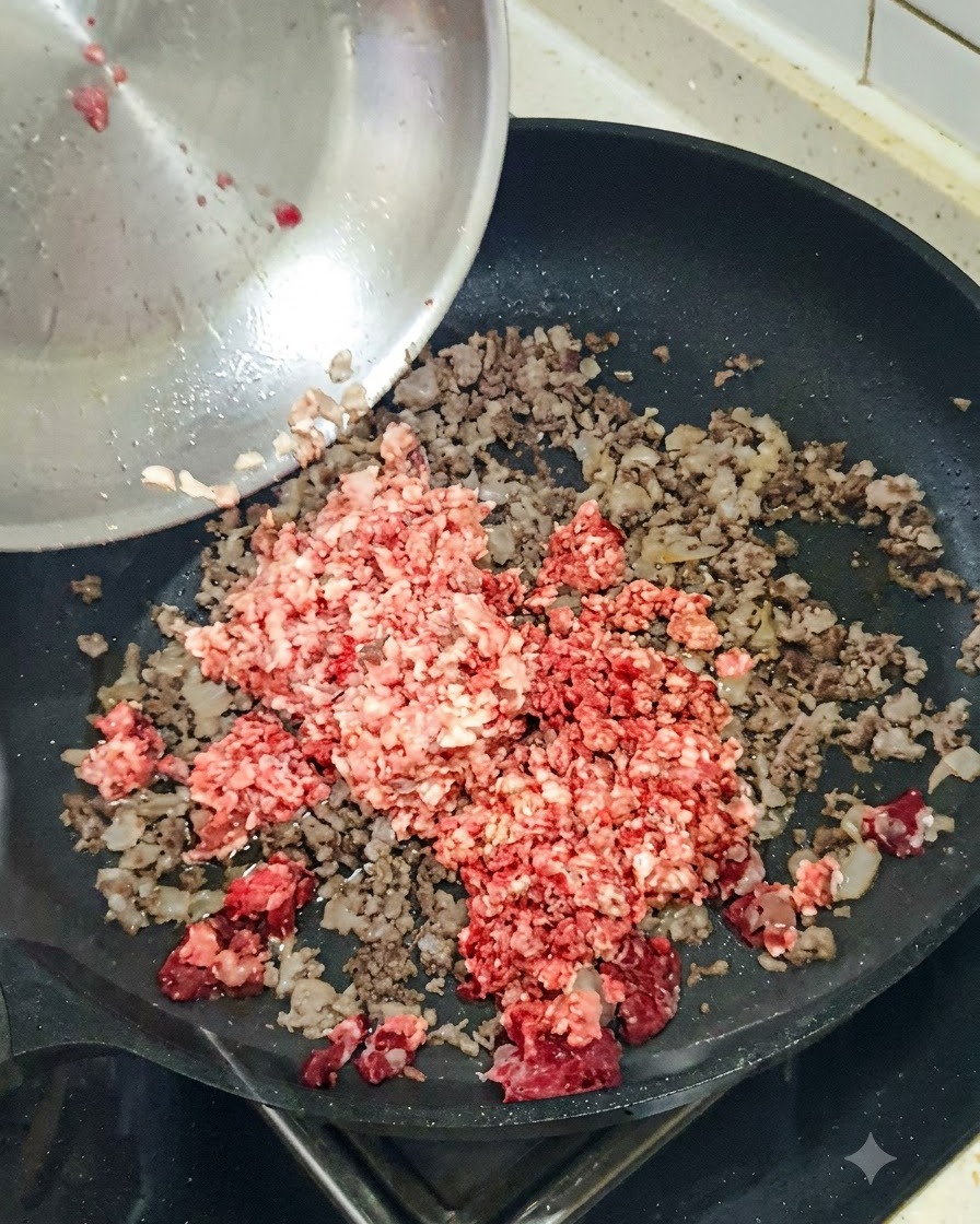 炒めたひき肉の入ったスキレットにみじん切りにした赤玉ねぎを入れているところ。