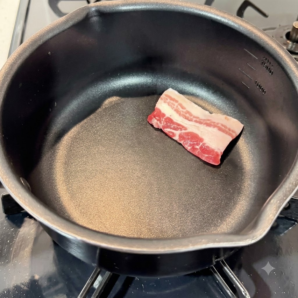 黒い調理鍋の中に並べられた生の状態の豚バラ肉の薄切り。