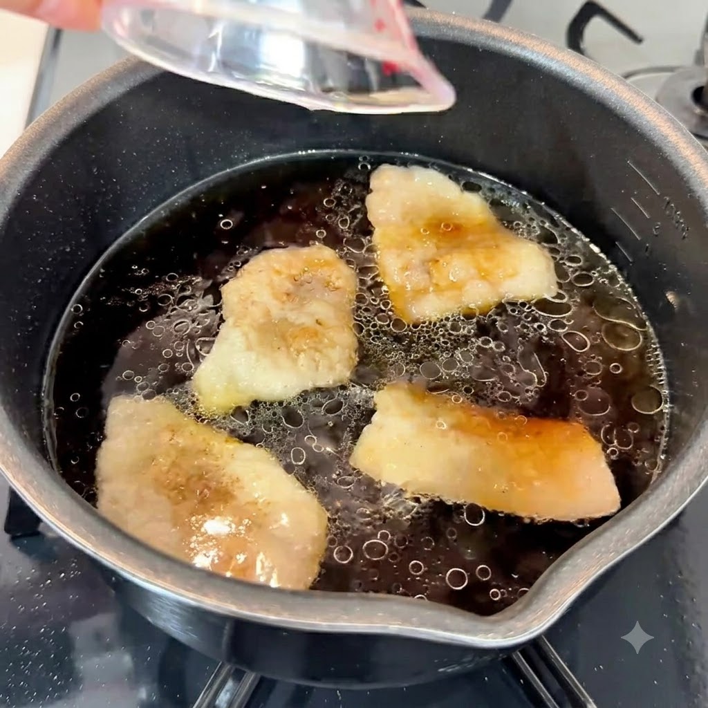 濃厚なスープのベースが入った鍋に、にんにくペースト、ごま油、白砂糖が加えられている様子。