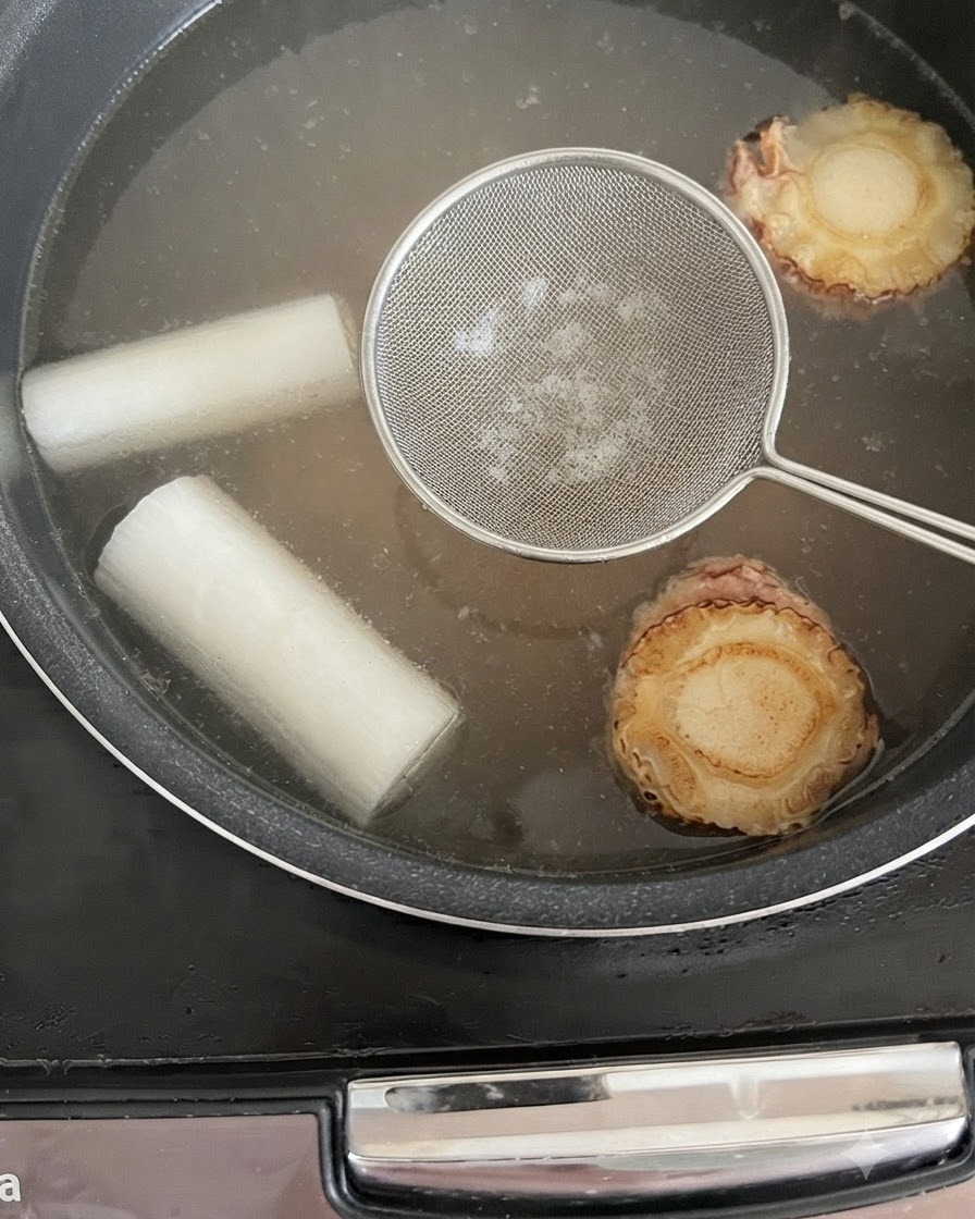 炊飯器のスープからアクをすくい取る様子。
