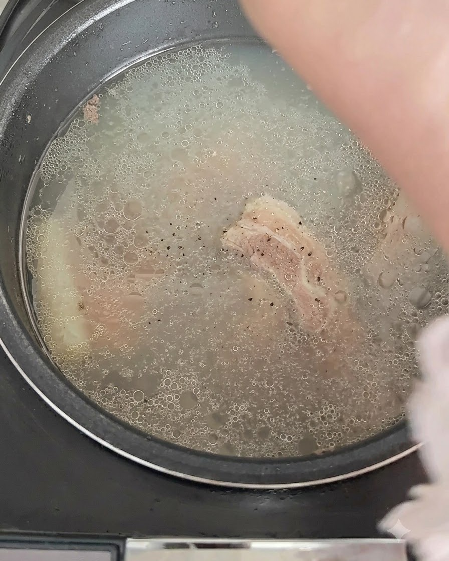 煮立つスープに黒こしょうが振られる様子。