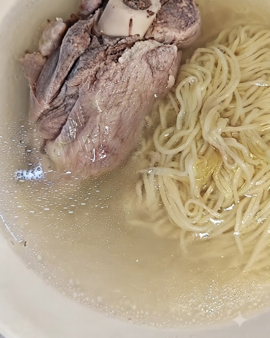 澄んだスープと茹で上がった麺が入ったラーメン鉢。