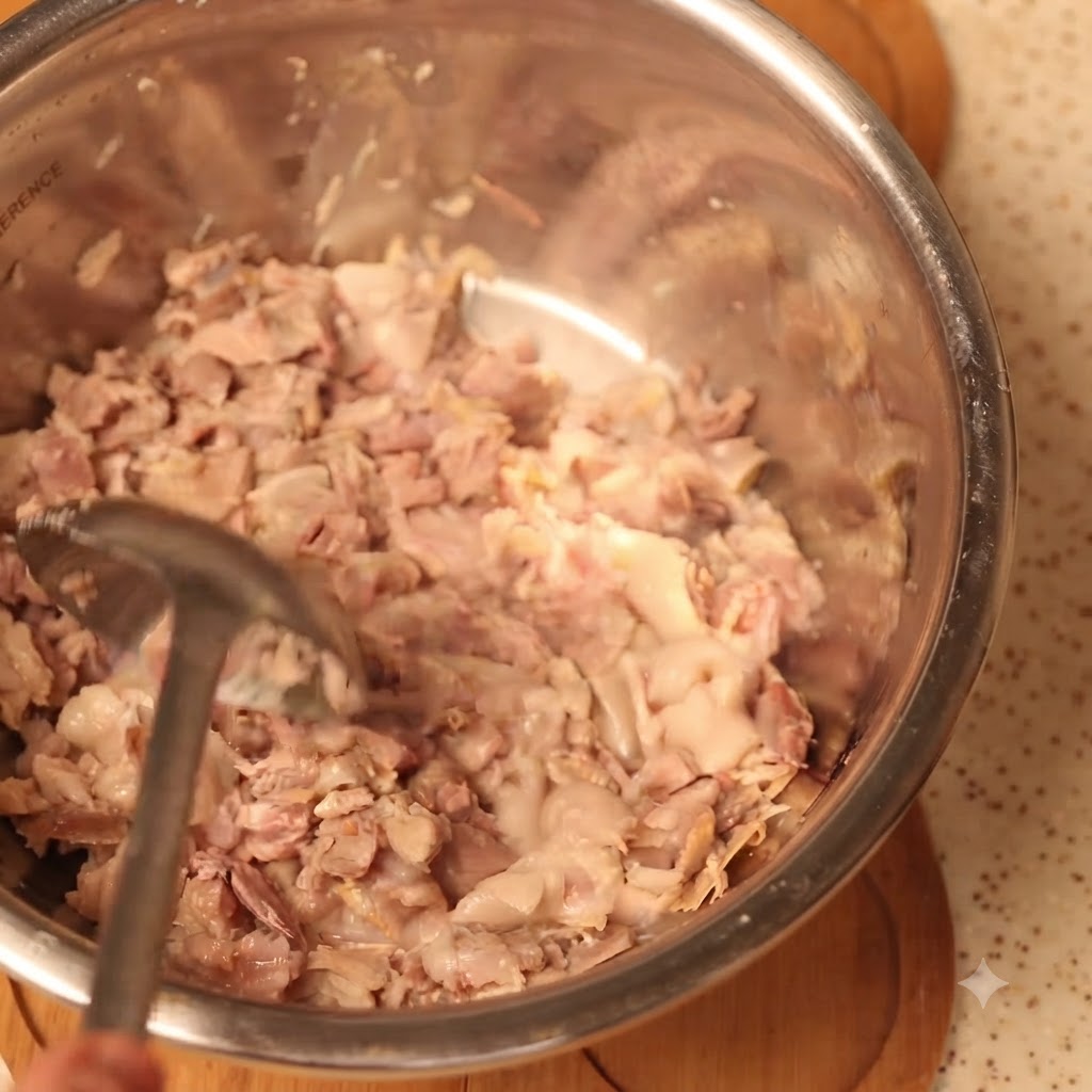 大きなボウルの中で調理された豚肉をしっかりと潰している様子