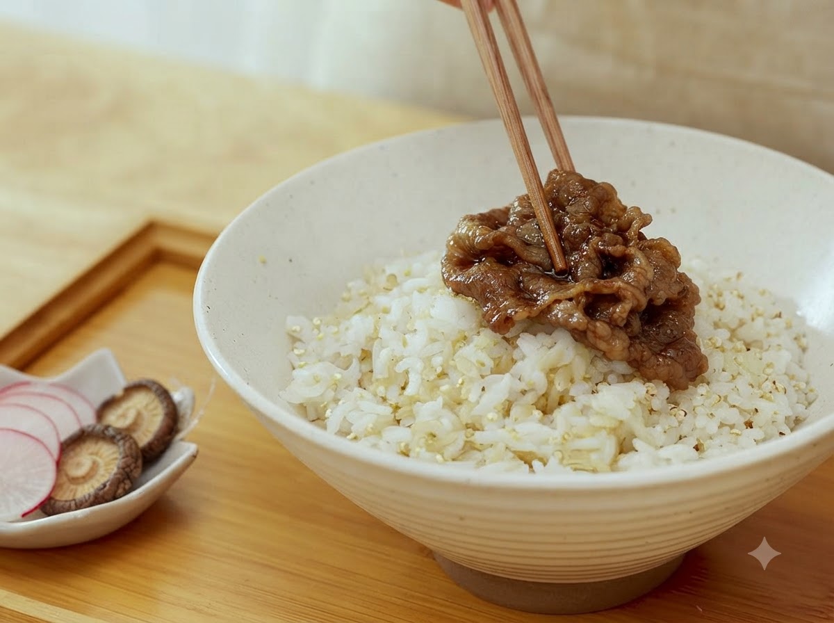 ご飯を盛った丼の上に、箸で調理した牛肉のスライスを載せているところ。