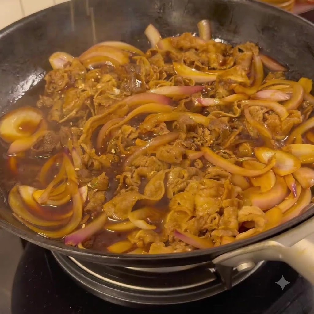 フライパンの中で、濃い色の美味しい照り焼きダレに牛肉と玉ねぎが煮絡められている様子。