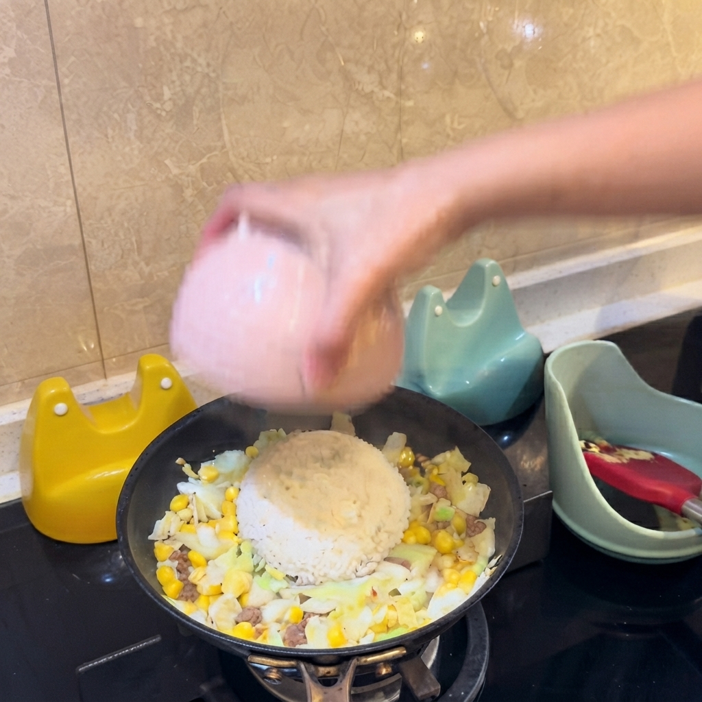 ピンク色のボウルをひっくり返し、白ご飯の山をフライパンの具材の中央に直接盛り付けている様子。
