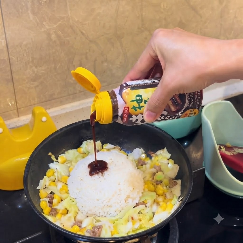 バーベキューソースのボトルから、フライパンの中央にあるご飯の山に向けて濃い色のソースを絞り出しているところ。