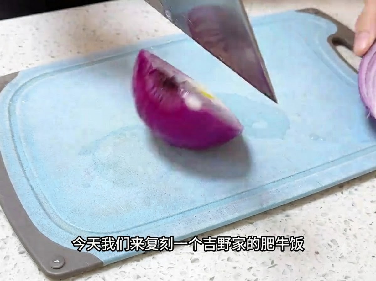 青いまな板の上で、包丁を使って赤玉ねぎを薄切りにしている様子
