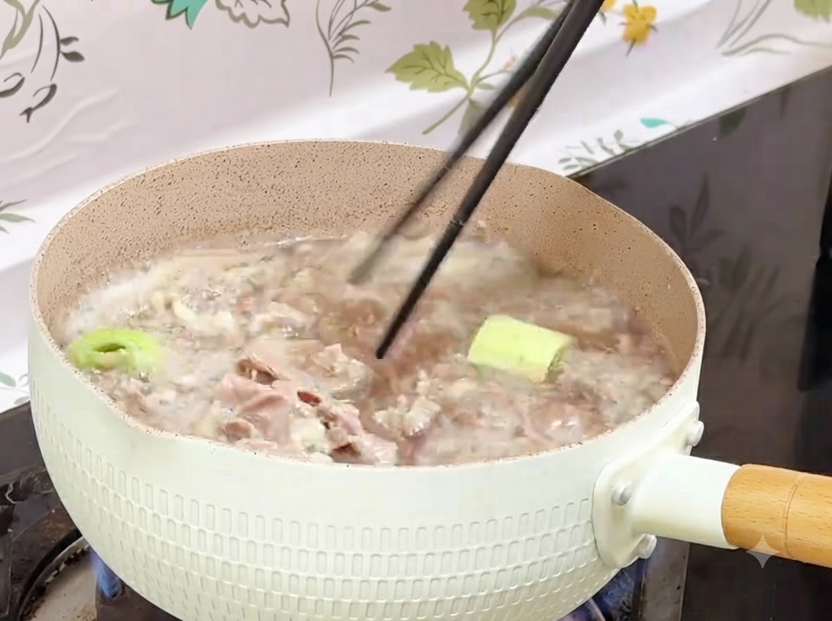 茹で上がった牛肉ロールを箸で鍋から容器へと移しているところ