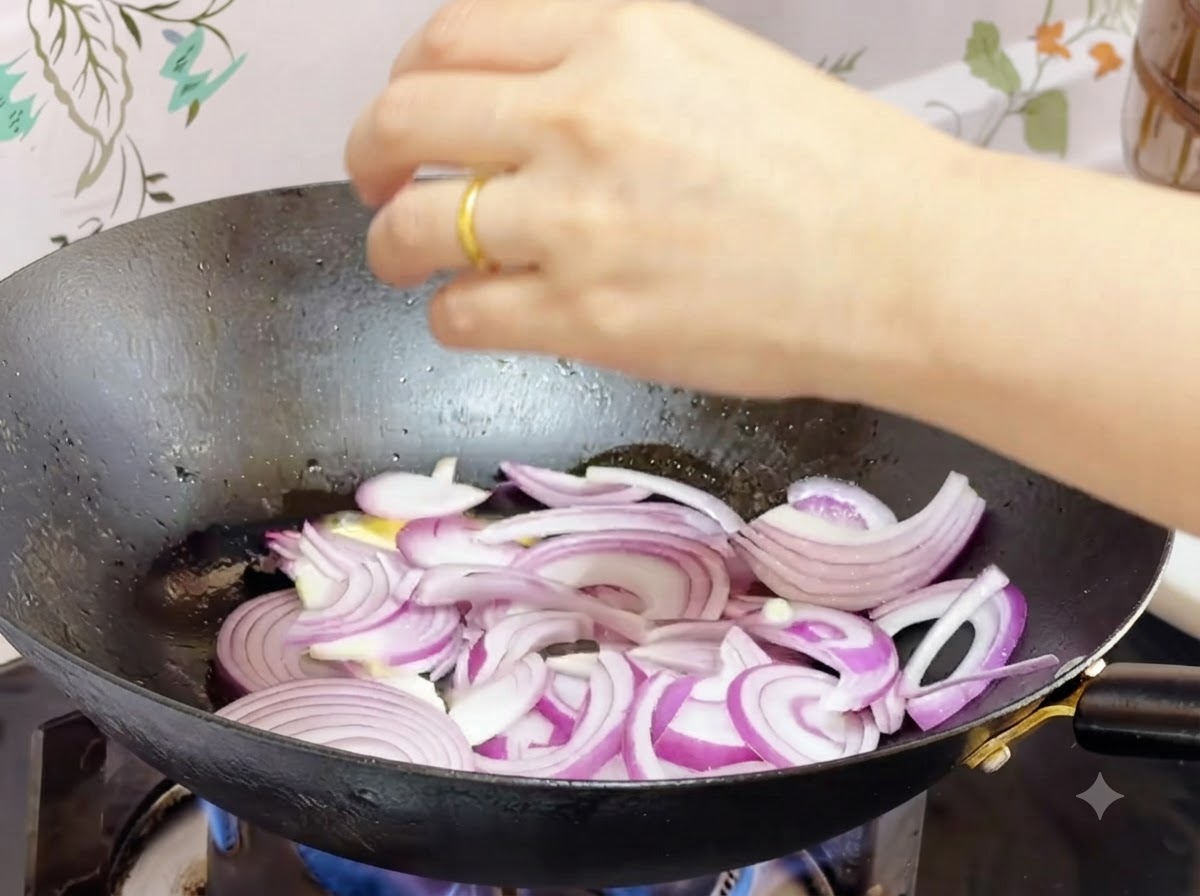中華鍋の中で溶けたバターと一緒にスライスした赤玉ねぎを炒めている様子