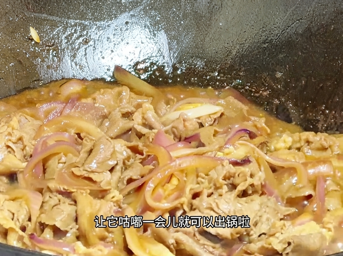 中華鍋の中で、とろみのついた泡立つタレの中で牛肉と玉ねぎが煮込まれているクローズアップ