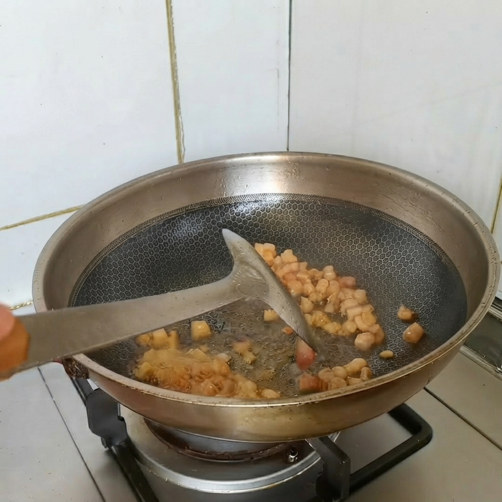 中華鍋で豚バラ肉の塊を香味野菜と一緒に炒めている様子。