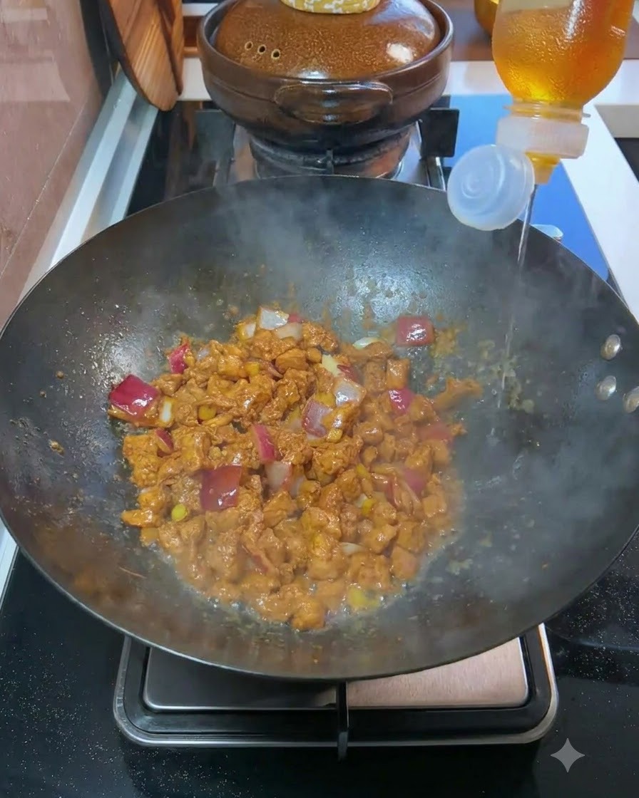 炒めた肉と玉ねぎが入った中華鍋に、ボトルから料理酒を注いでいる様子。