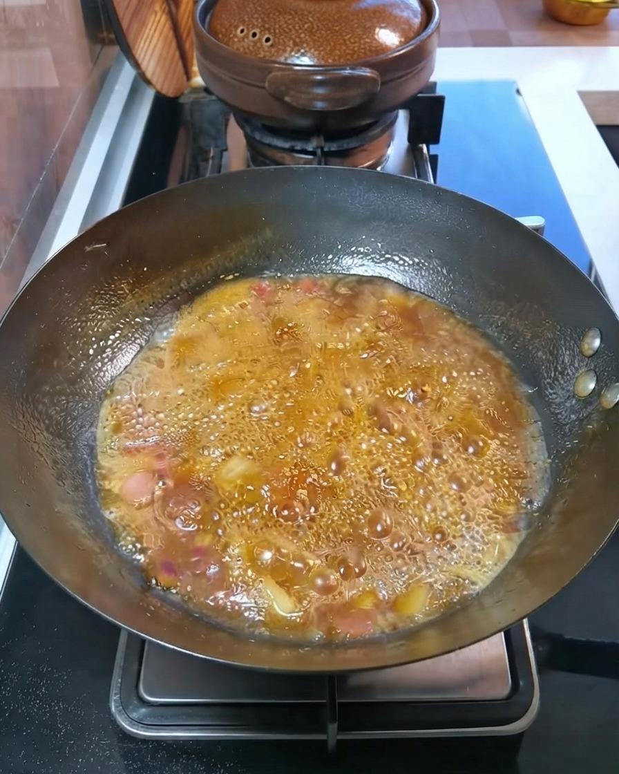 中華鍋の中で、角切りのじゃがいもとにんじんがグツグツと煮込まれている様子。