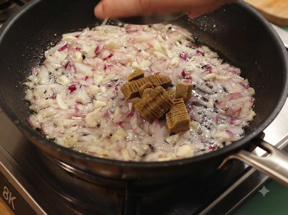 炒めた玉ねぎとにんにくが入ったフライパンに、スライスしたカレールーを入れている様子。