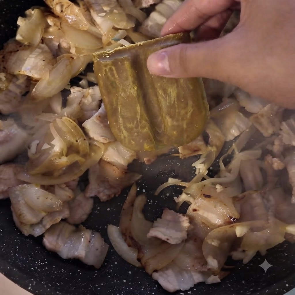 肉と玉ねぎが入ったフライパンにカレールーのブロックを加えている様子