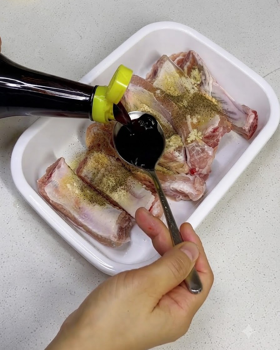 スペアリブに醤油やオイスターソースなどの調味料をかけている様子。