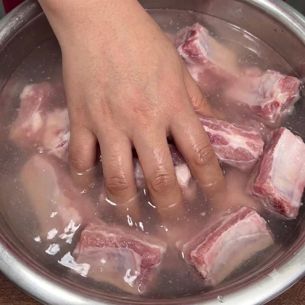手でボウルの中の豚肉と重曹水をしっかりと混ぜ合わせている様子。