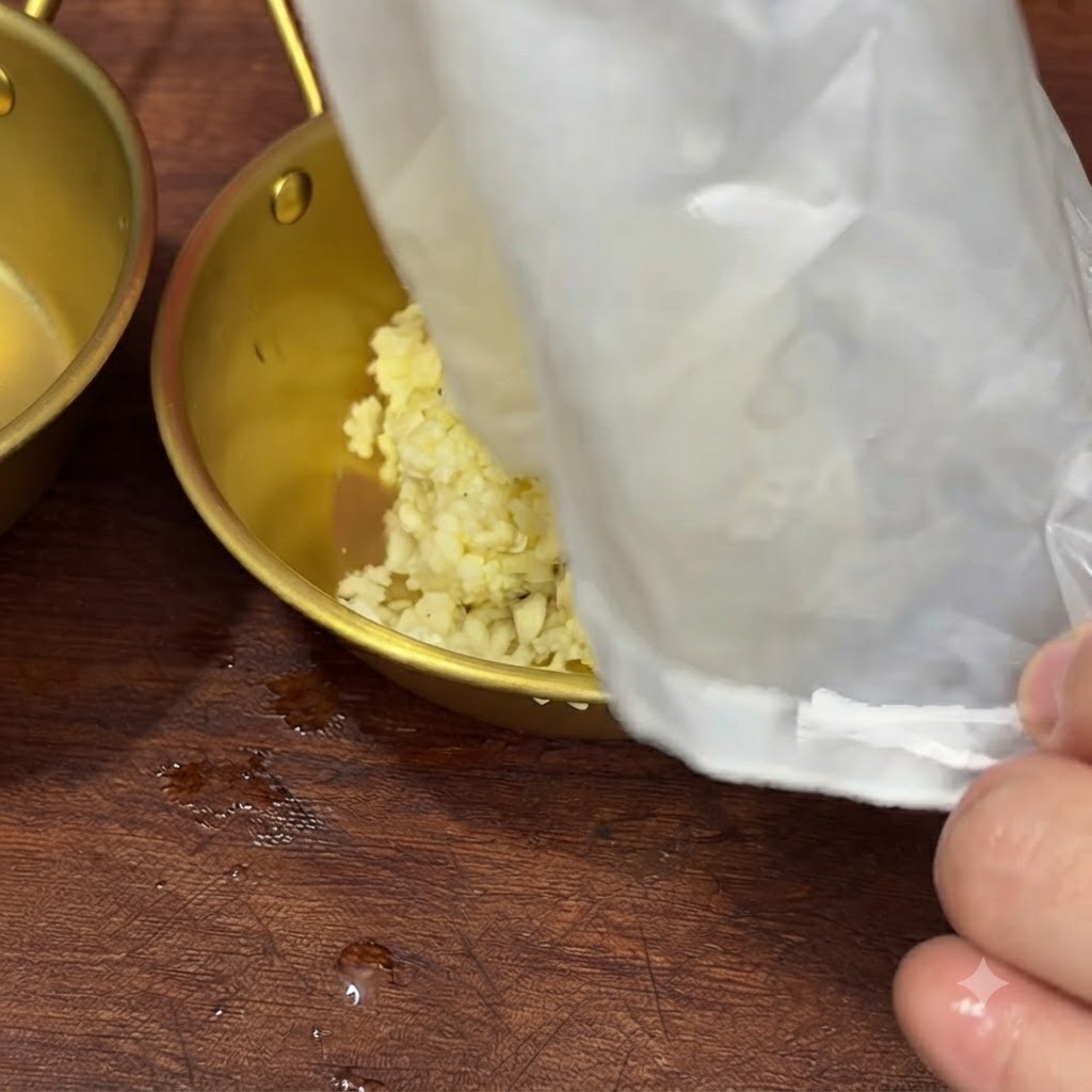 濾し袋に残ったにんにくの搾りかすをボウルに移している様子。