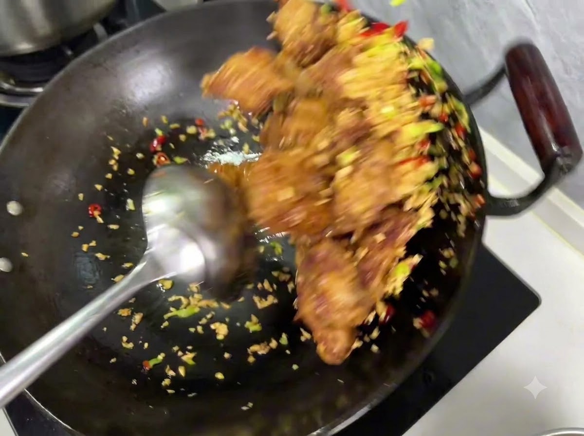 中華鍋の中で、豚肉とにんにくの混合物の上に塩胡椒が振りかけられている様子。