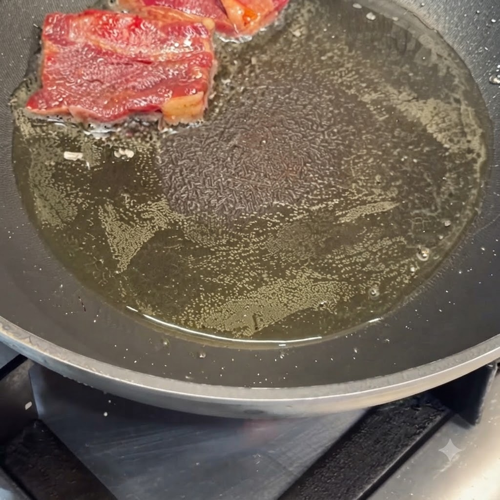 熱したフライパンの油で下味をつけた牛カルビを焼いている様子。