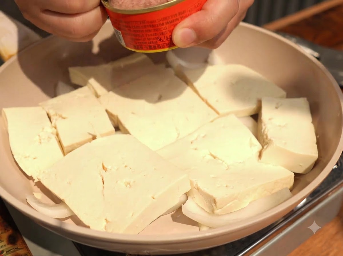 並べた豆腐の中央に、ツナ缶の身をスプーンですくって乗せている様子。