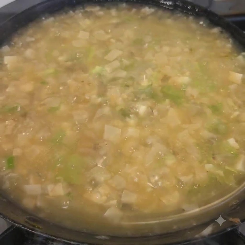 鍋の中の仕上がったスープに刻んだパクチーを振りかけている様子。
