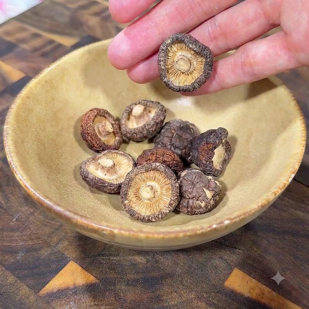 木製の台の上の黄色いセラミックボウルに入っている乾燥椎茸。cite: 1