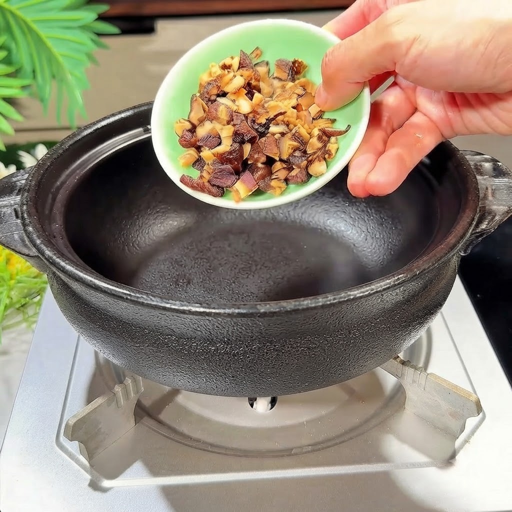 加熱した黒い土鍋に細かく切った干し椎茸を投入している様子。cite: 1