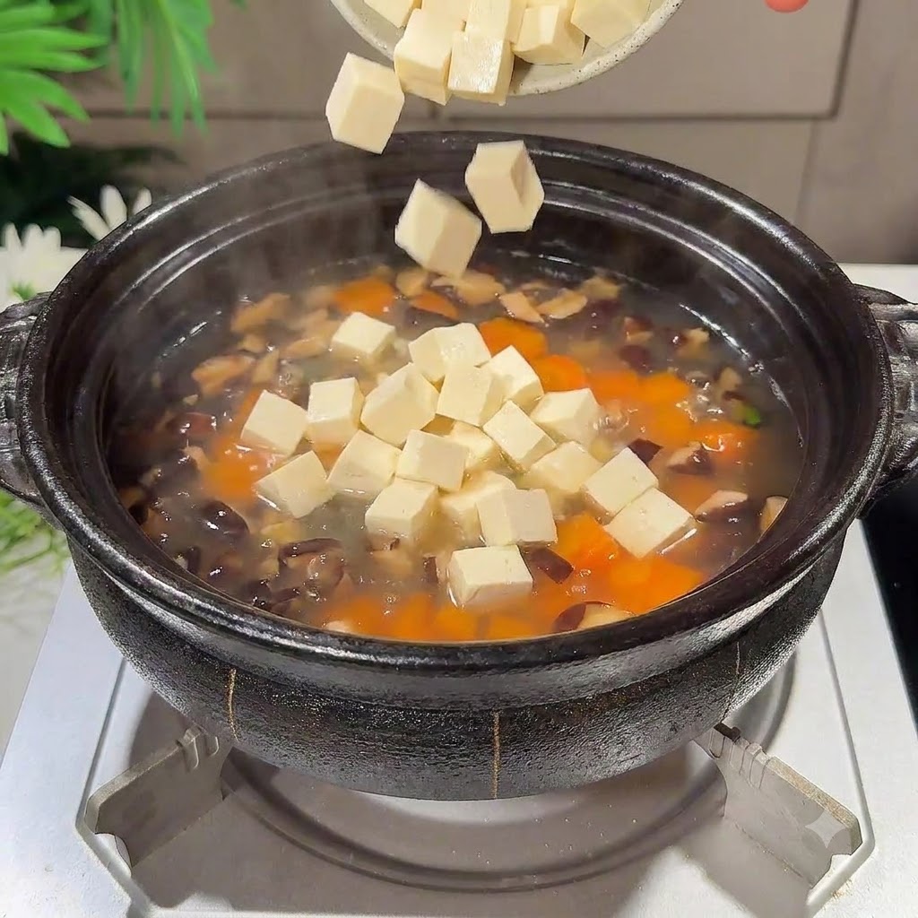 煮立っているスープの鍋の中に、サイコロ状の絹ごし豆腐のピースが入っていく様子。cite: 1