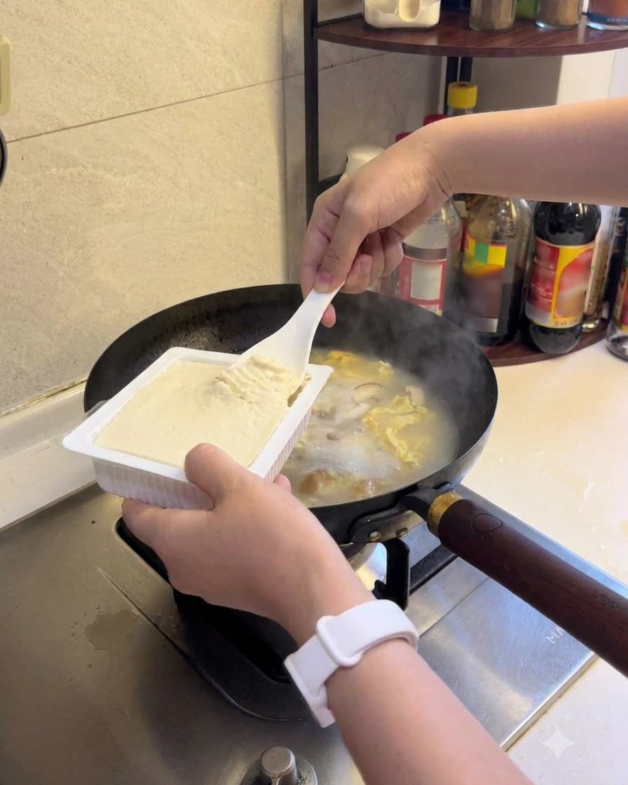 煮立っているスープに絹ごし豆腐を加えている様子。