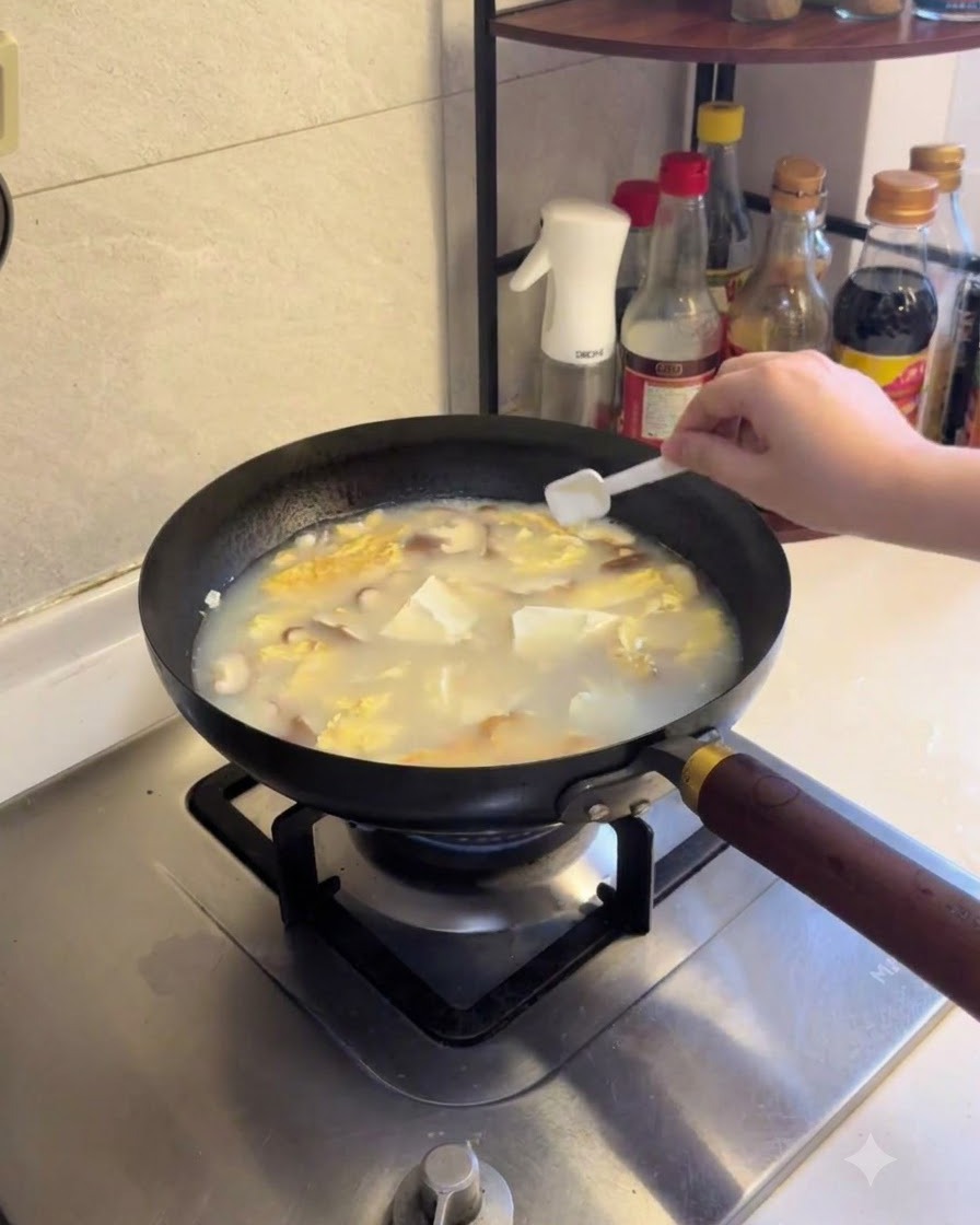 豆腐とキノコのスープに塩と白コショウを振りかけている様子。