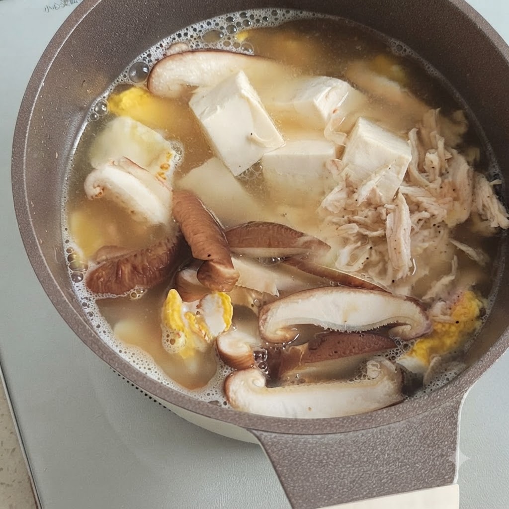 煮立っている豆腐、きのこ、卵のスープの上に、干しエビがこんもりと乗っている様子