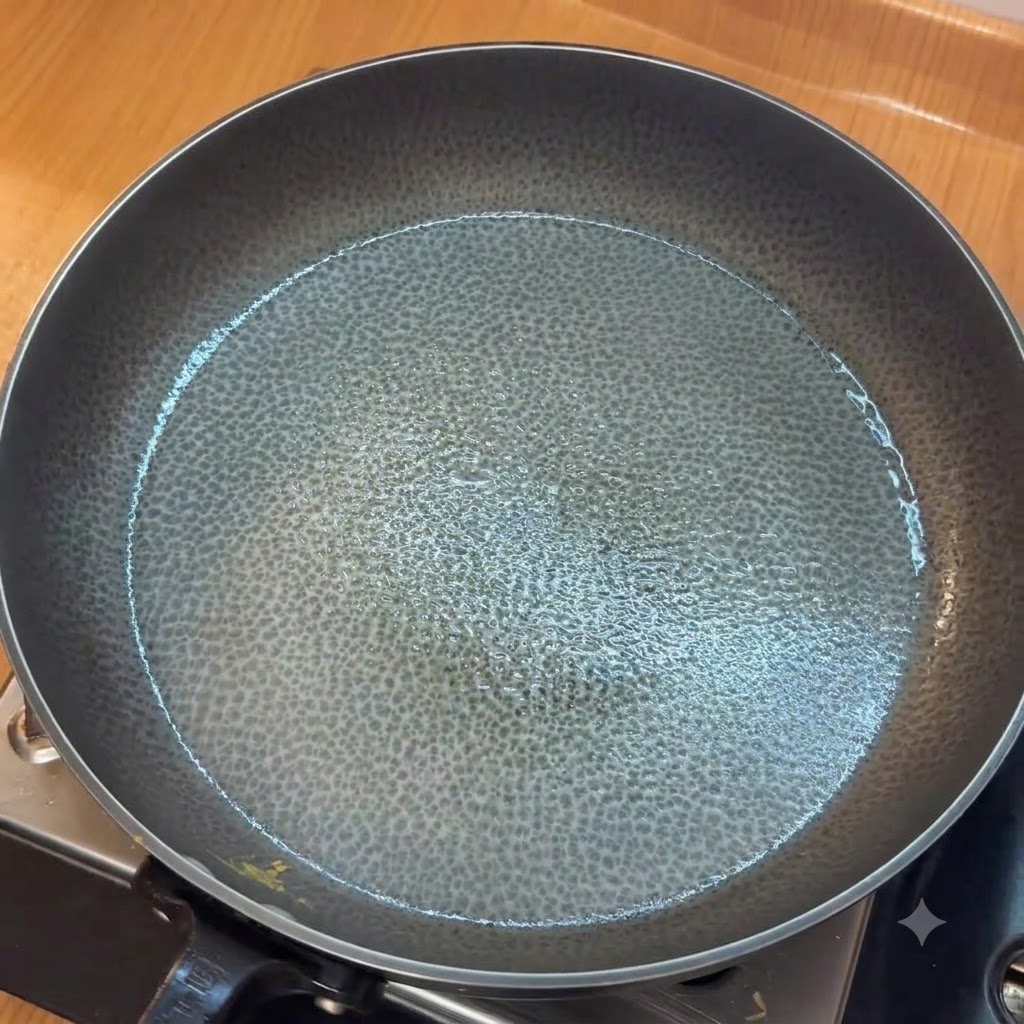 油を引いたフライパンでみじん切りにんにくを炒め、その後に刻んだトマトを加えている様子。