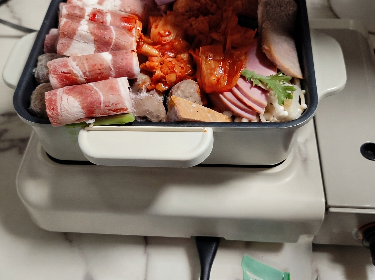 肉、野菜、お餅を並べた鍋にスープを注いでいる様子。