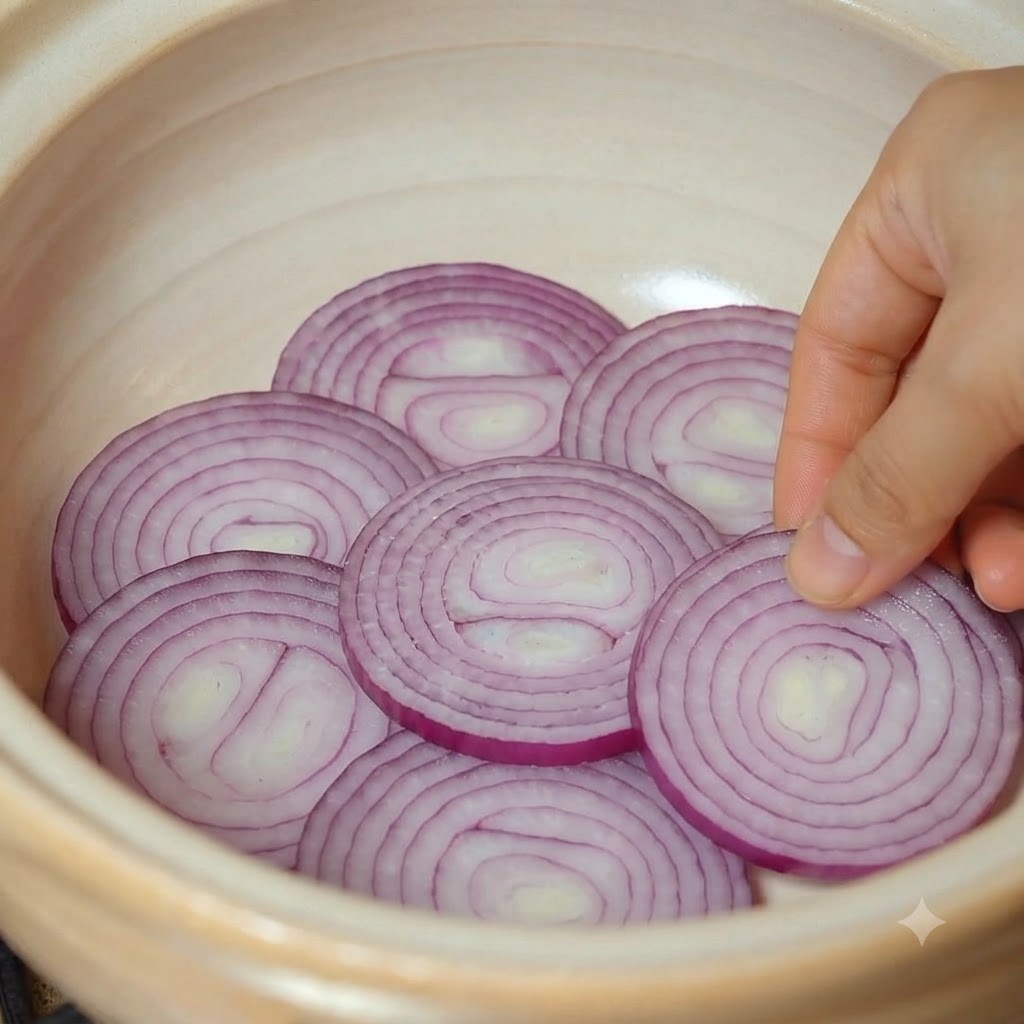 スライスした赤玉ねぎを土鍋の底に綺麗に並べている様子。