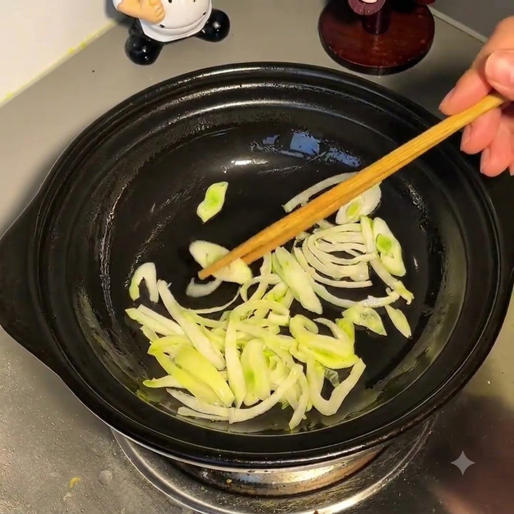 炒めた青ネギが入った鍋に、上から水が注がれている様子。