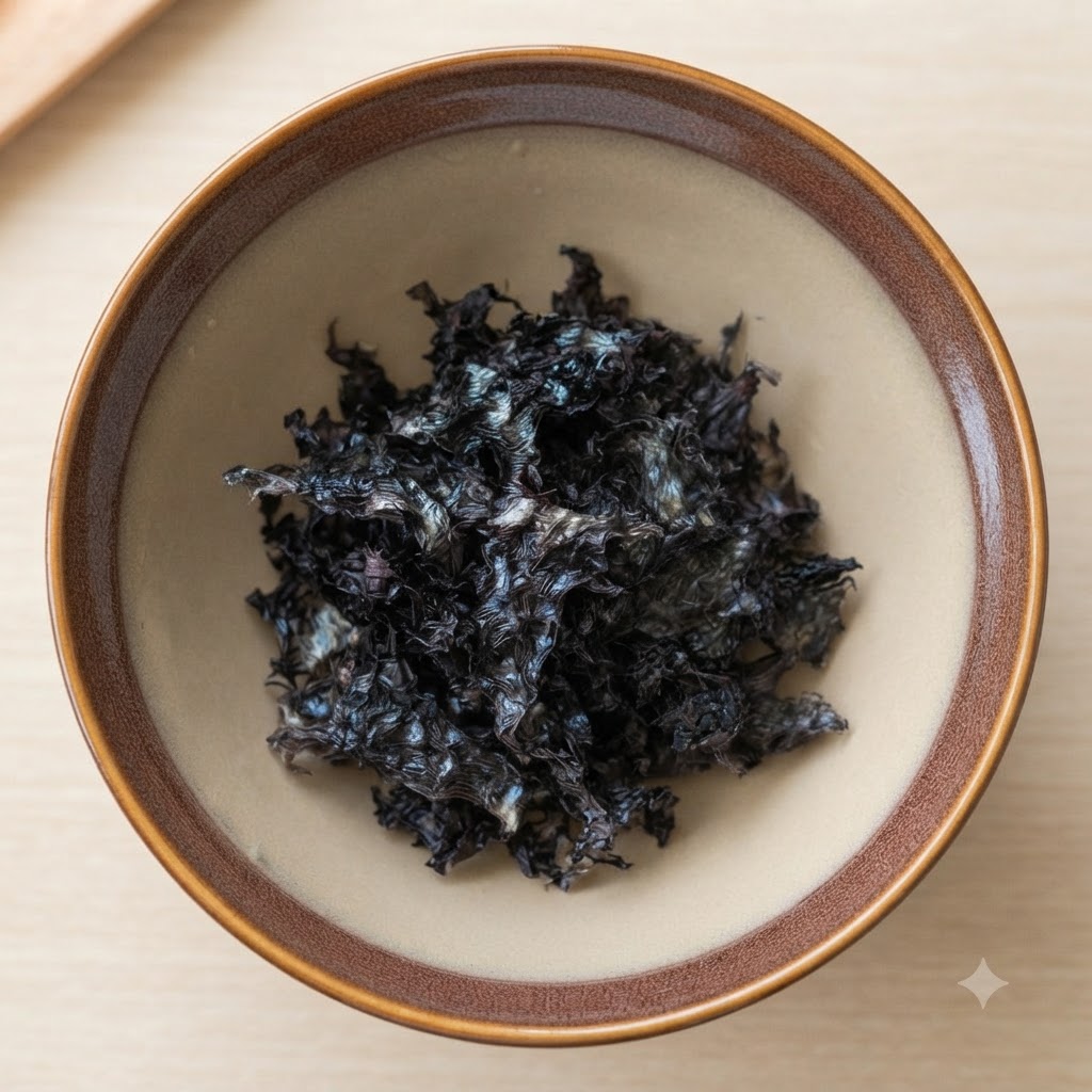 茶色の陶器の器の底に入っている乾燥海藻フレークと白ごま。