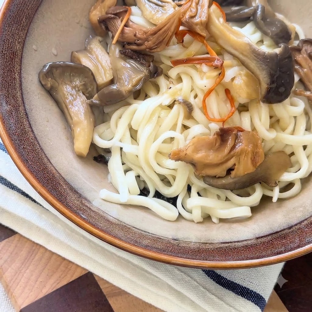 サービングボウルの麺の上から、熱々のきのこスープと旨味のある調理されたきのこをおたまですすいでいる様子。