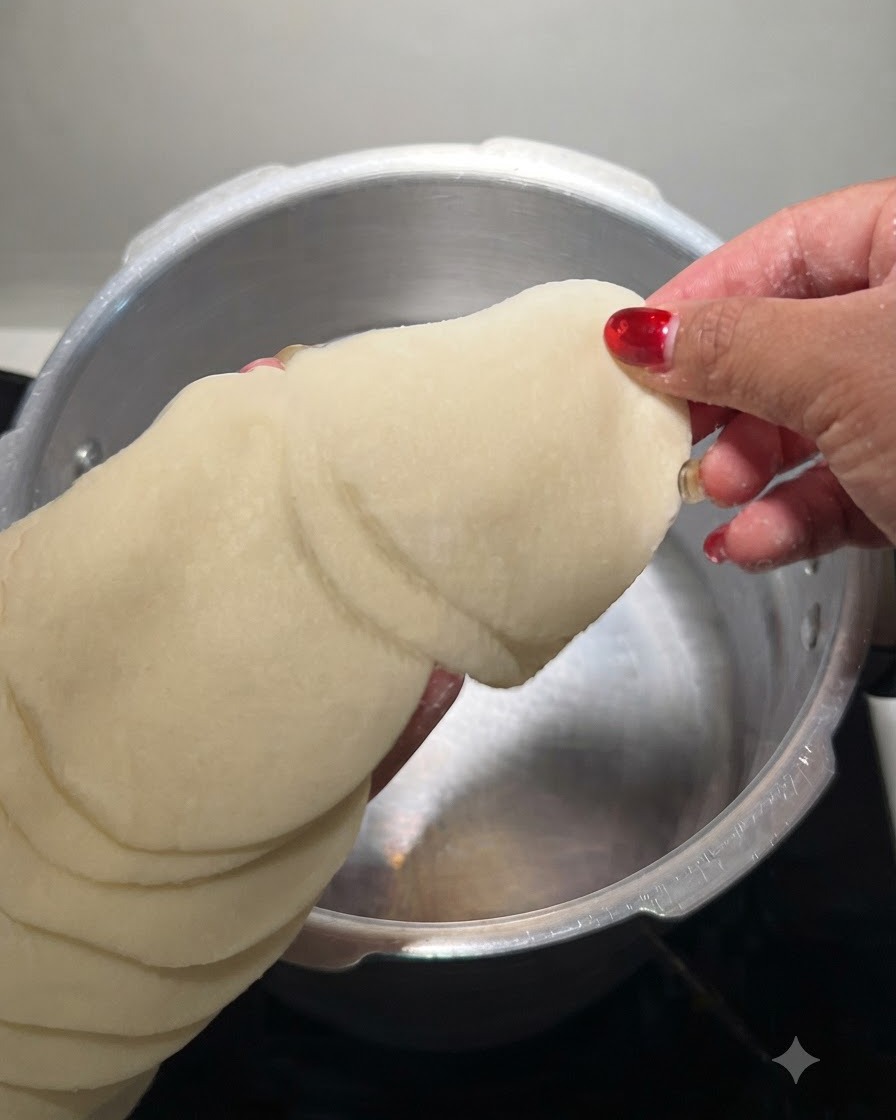 丸い餃子の皮の束を手に持ち、冷水の入った金属製の鍋に浸しているところ。